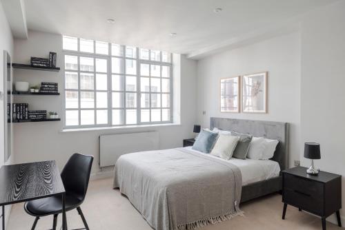 a white bedroom with a bed and a chair at London's Calling - Farringdon - by Frankie Says in London