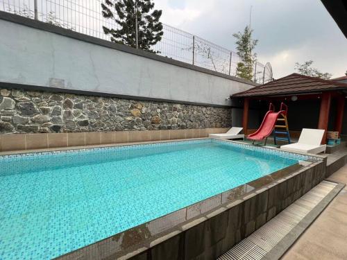 una gran piscina con 2 sillas junto a un edificio en Vila Nio en Bogor