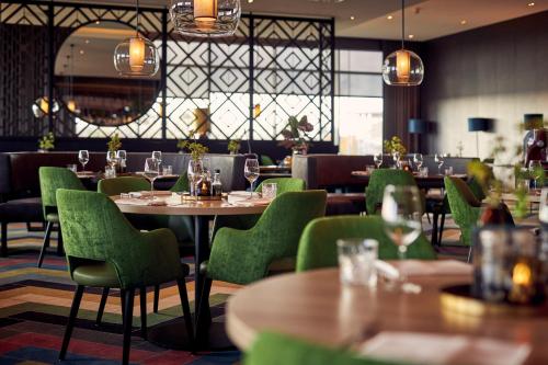 レーワルデンにあるVan der Valk Hotel Leeuwardenの木製テーブルと緑の椅子が備わるレストラン