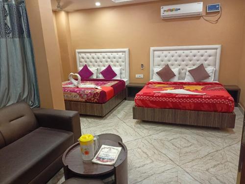 a hotel room with two beds and a couch at HOTEL HARIHAR in Haridwār