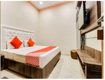 HOTEL HARIHAR في حاريدوار: غرفة نوم مع سرير ووسائد برتقالية عليه