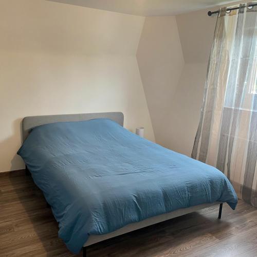 - un lit avec une couette bleue dans une chambre dans l'établissement Maison de charme à 5 min de Disney Paris, à Villeneuve-Saint-Denis