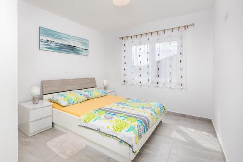 a white bedroom with a bed and a window at Apartments Tea in Malinska