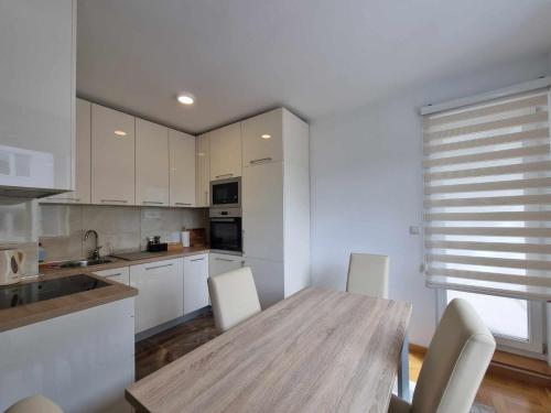 Una cocina con una mesa de madera y gabinetes blancos. en Apartman Tesla Pale, en Pale