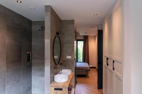 uma casa de banho com 2 lavatórios e um chuveiro em De Witte Bergvliet em Oosterhout