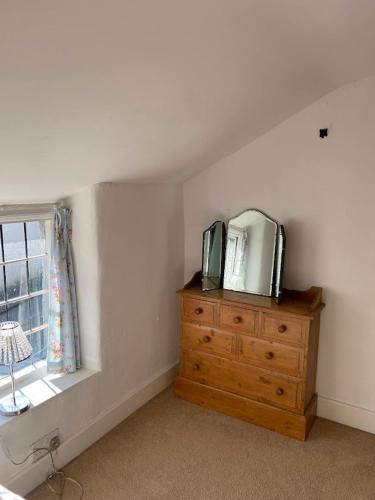 a bedroom with a dresser with a mirror and a window at Thatched Cottage, beautiful village near the sea in Otterton
