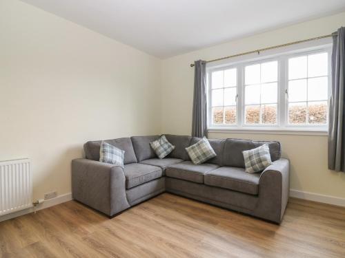 a living room with a couch and a window at Bankhead of Lour Bungalow in Forfar