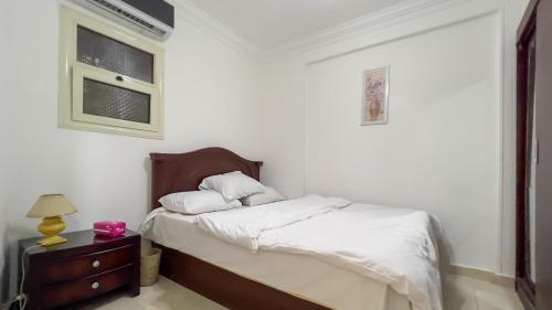 開羅的住宿－الجيزه هرم شارع ابو الهول السياحي，一间卧室配有一张带白色床单的床和床头柜。