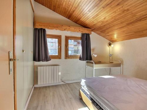 une chambre avec un lit et un plafond en bois dans l'établissement Duplex calme au pied des pistes, balcon et animaux acceptés - FR-1-455-232, à La Plagne Tarentaise