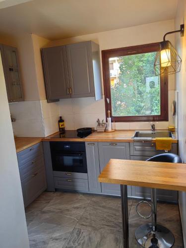 d'une cuisine avec des placards gris, un évier et une fenêtre. dans l'établissement Paris La Defense - Courbevoie Seine view - very near Metro 3, à Courbevoie