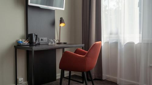 a desk with a red chair next to a window at Quality Hotel Augustin in Trondheim