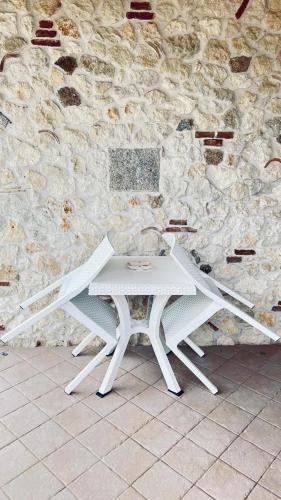 a white table in front of a stone wall at B&B Casale Pietrantica Tropea in Ciaramiti