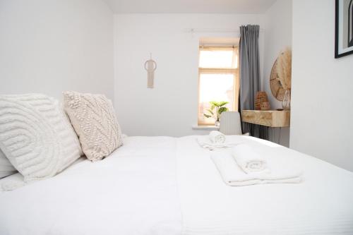 ein weißes Bett mit weißen Kissen und einem Fenster in der Unterkunft Central Cardiff - 3 Bedroom Home - Walk to Shopping Town Centre And Cardiff Castle in Cardiff