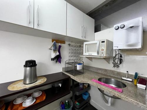 a kitchen with white cabinets and a sink and a microwave at Hospedagem BRASILIANAS in Brasilia