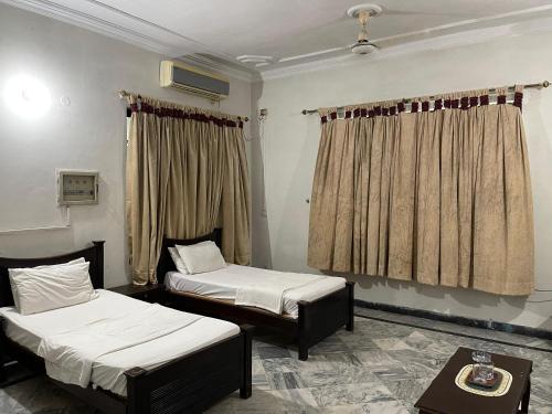 um quarto com duas camas e uma mesa em Islamabad lodge em Islamabad