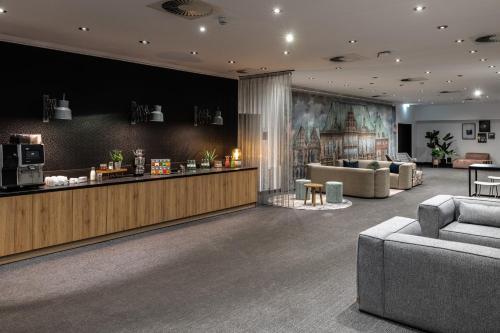 a lobby with a waiting area with couches and a counter at Pentahotel Bremen in Bremen