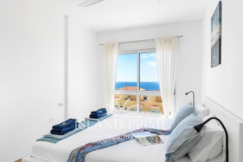 um quarto com uma cama e uma janela com o oceano em Breathtaking Panoramic Views in Golf del Sur em San Miguel de Abona