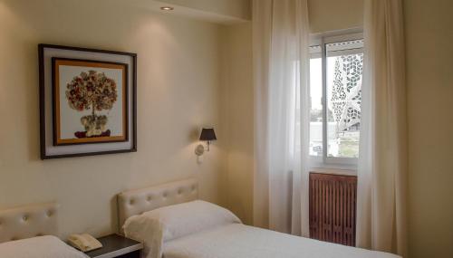 a hotel room with two beds and a window at Hotel Viña de Italia in Cordoba