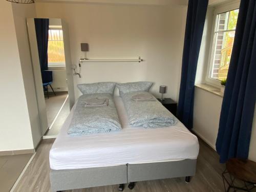 a bed in a small room with blue curtains at Haus Osterstraße in Norden