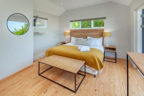 a bedroom with a bed and a table and a mirror at Villa Blu Guesthouse in Hermanus