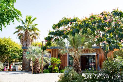 a building with palm trees in front of it at Au Paradis des Campeurs in Les Issambres