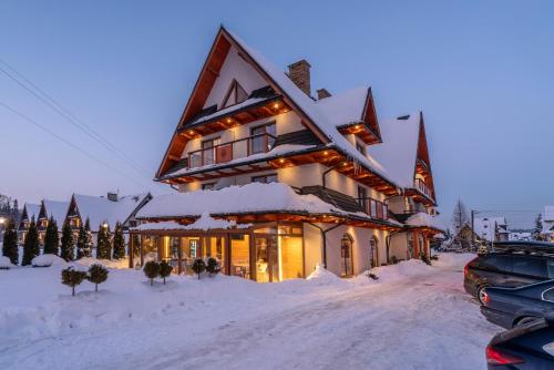 a large building covered in snow in a parking lot at Parzenica B&B in Białka Tatrzańska