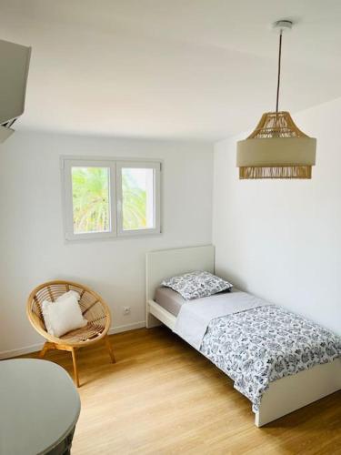 une chambre avec un lit, une chaise et une fenêtre dans l'établissement La Villa du Roc, grandiose, 5mn à pied de la mer, à Fréjus