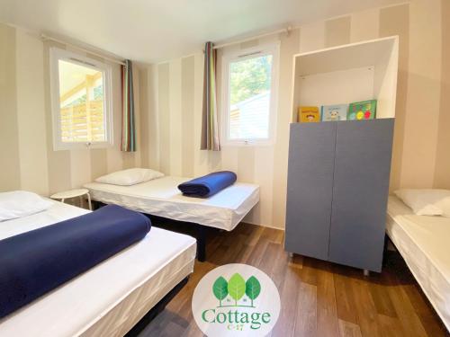 two beds in a room with two windows at Cottage C17 – proche Europapark in Boofzheim