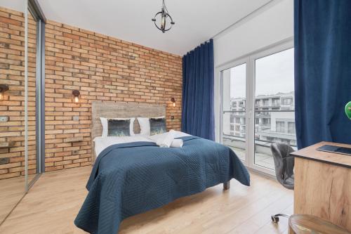 een slaapkamer met een bed en een bakstenen muur bij Beautiful Apartment with Spacious Balcony by Renters in Wrocław