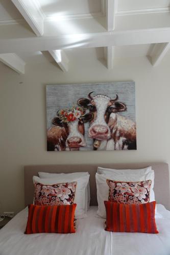 a bedroom with a painting of cows on the wall at Melkmeisje in Oudeschild