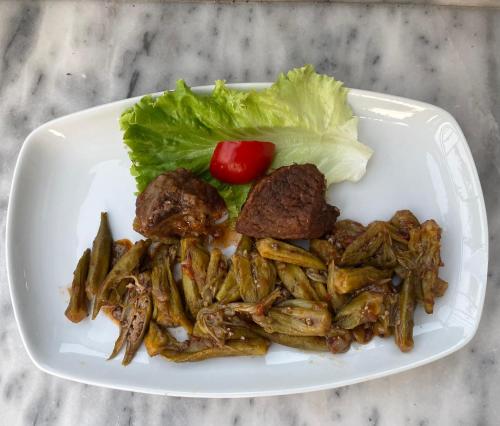 a white plate of food with meat and lettuce at Hotel Aroma in Përmet