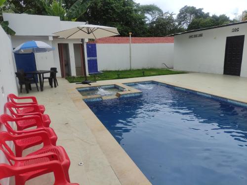 a swimming pool with a red chair and an umbrella at Casa Quinta el Refugio in Flandes