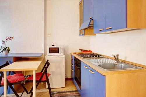 a kitchen with blue cabinets and a sink and a table at Foresteria al Cantun in Sondrio