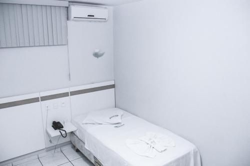 Habitación blanca con cama y teléfono. en Delta Hotel Rondonopolis, en Rondonópolis
