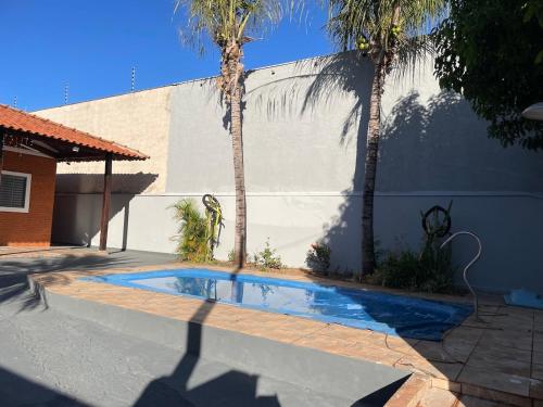 a swimming pool in front of a house with palm trees at Rancho próximo rio pesca Sales in Sales