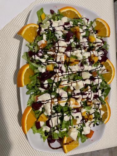 a white plate with a salad with orange slices at Hotel Aroma in Përmet