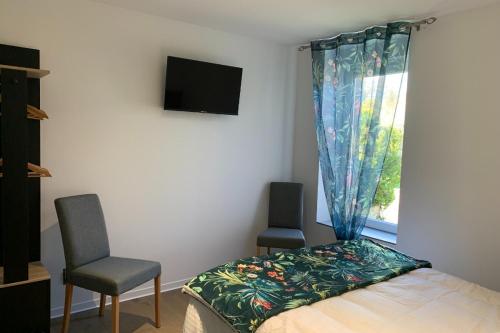 a bedroom with a bed and two chairs and a window at Appartement RDC in Remoncourt