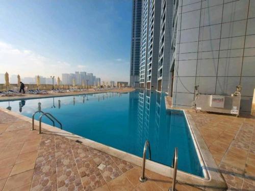 a large swimming pool on the side of a building at Cozy 1BH Apt next to the sea! in Ajman 