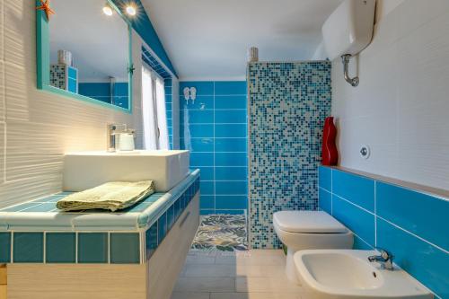 a blue bathroom with a sink and a toilet at Villetta Lucia a due passi dal mare in Putzu Idu