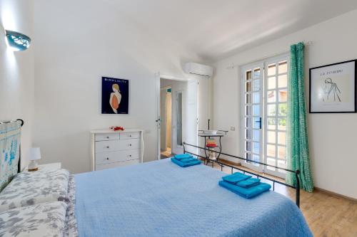 a bedroom with a blue bed and a window at Villetta Lucia a due passi dal mare in Putzu Idu