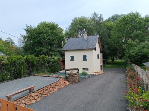 a house with a driveway next to a building at Maisonnette en bord de rivière tout près du Mans in La Bazoge