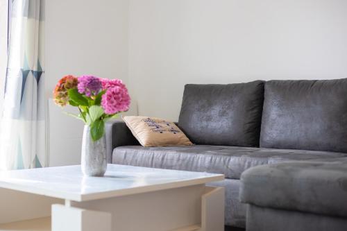 a living room with a couch and a vase of flowers on a table at Gîte du Port sur la presqu'île de Lézardrieux in Lézardrieux