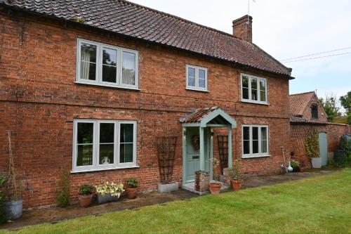 a brick house with a blue door and windows at Leo's Holiday Cottage in Doddington