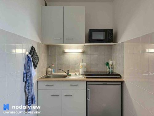 une petite cuisine avec un évier et un micro-ondes dans l'établissement Ipanema, à Canet