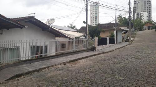 une rue vide avec une clôture blanche et des bâtiments dans l'établissement CASA PARA OKTOBERFEST 12 PESSOAS., à Blumenau