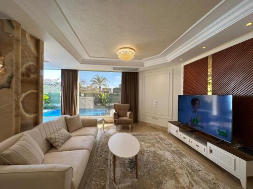a living room with a couch and a flat screen tv at Al Sawah Stand Alone Villa With Private Pool in Sheikh Zayed