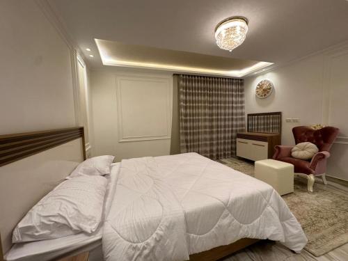 a bedroom with a white bed and a chair at Al Sawah Stand Alone Villa With Private Pool in Sheikh Zayed
