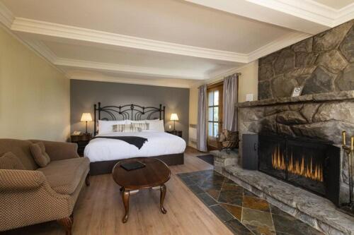 a bedroom with a bed and a fireplace at Auberge des Nuages in La Malbaie