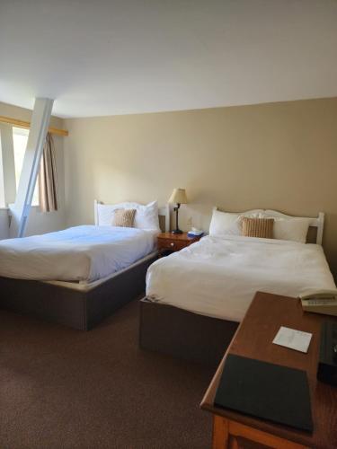 a hotel room with two beds and a table at Auberge des Nuages in La Malbaie
