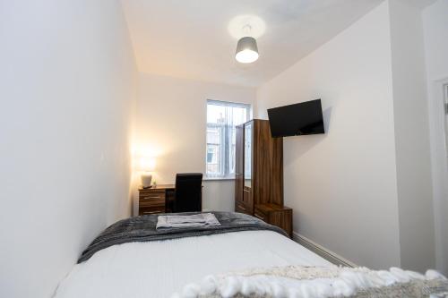 a bedroom with a bed and a tv on the wall at M6 Guest House in Manchester
